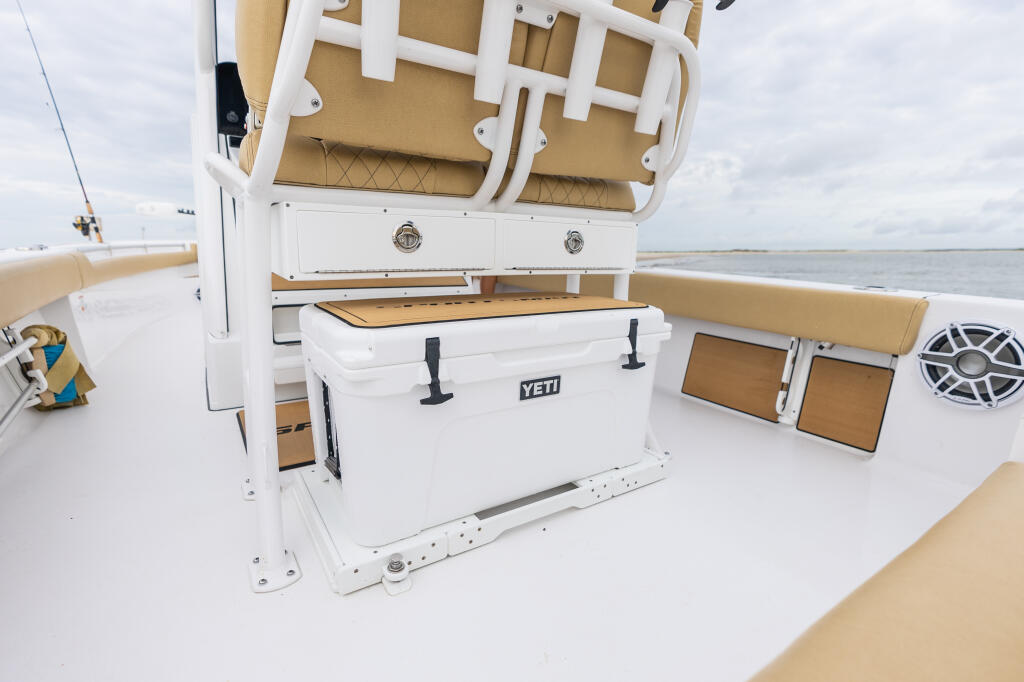 White YETI cooler and storage compartments on boat deck with tan cushioned seating and hard-top canopy