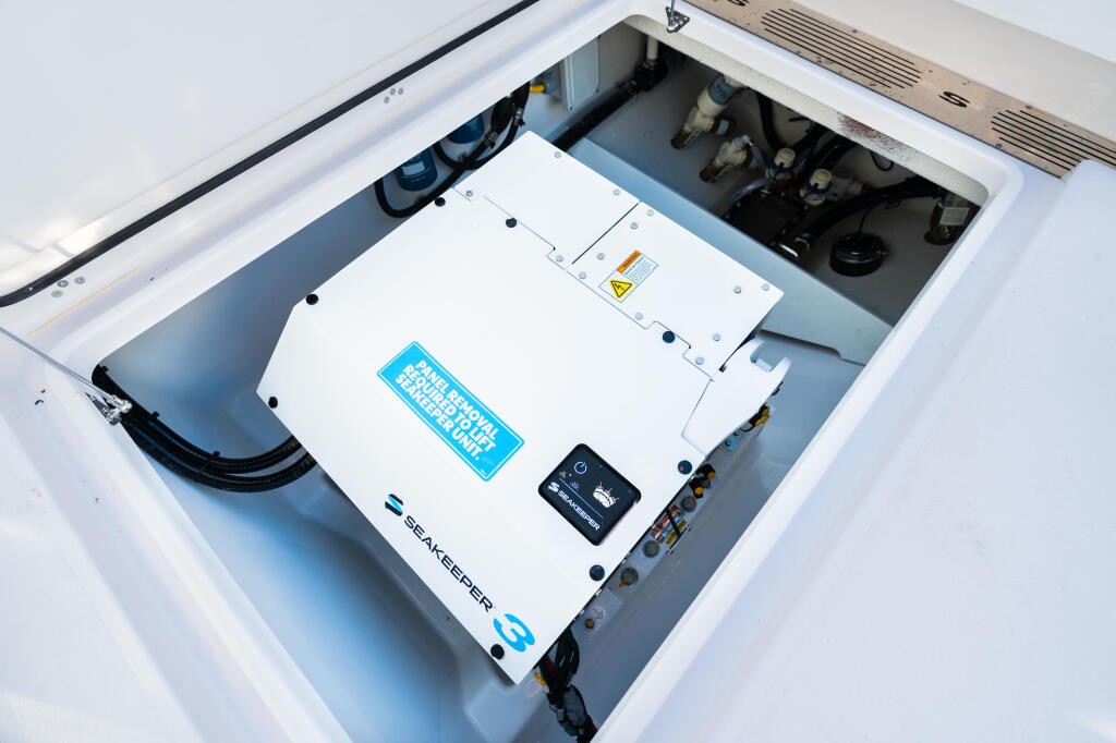 Open compartment revealing SeaKeeper gyroscope stabilization system and marine electronics mounted on white backing plate