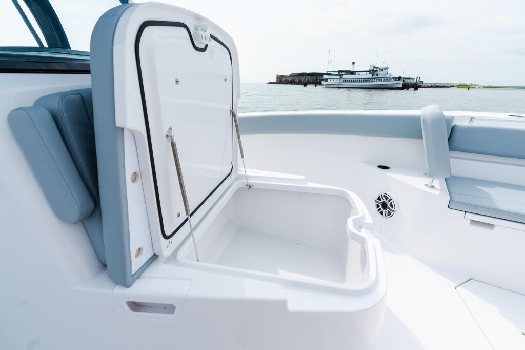 Open livewell and cooler storage on boat deck with marina and vessel in background