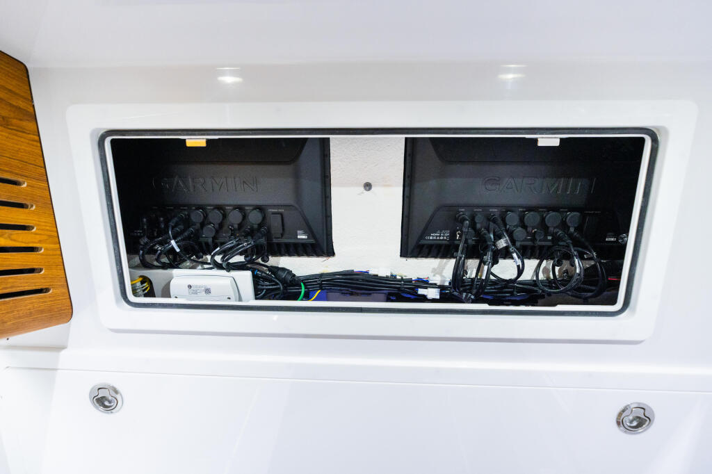 Dual Garmin touchscreen displays with electronics and wiring in boat helm storage compartment