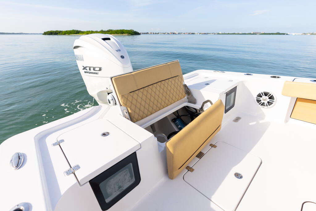 Open rear hatch on white Masters 267OE boat with tan cushioned seating and electronics display on calm water