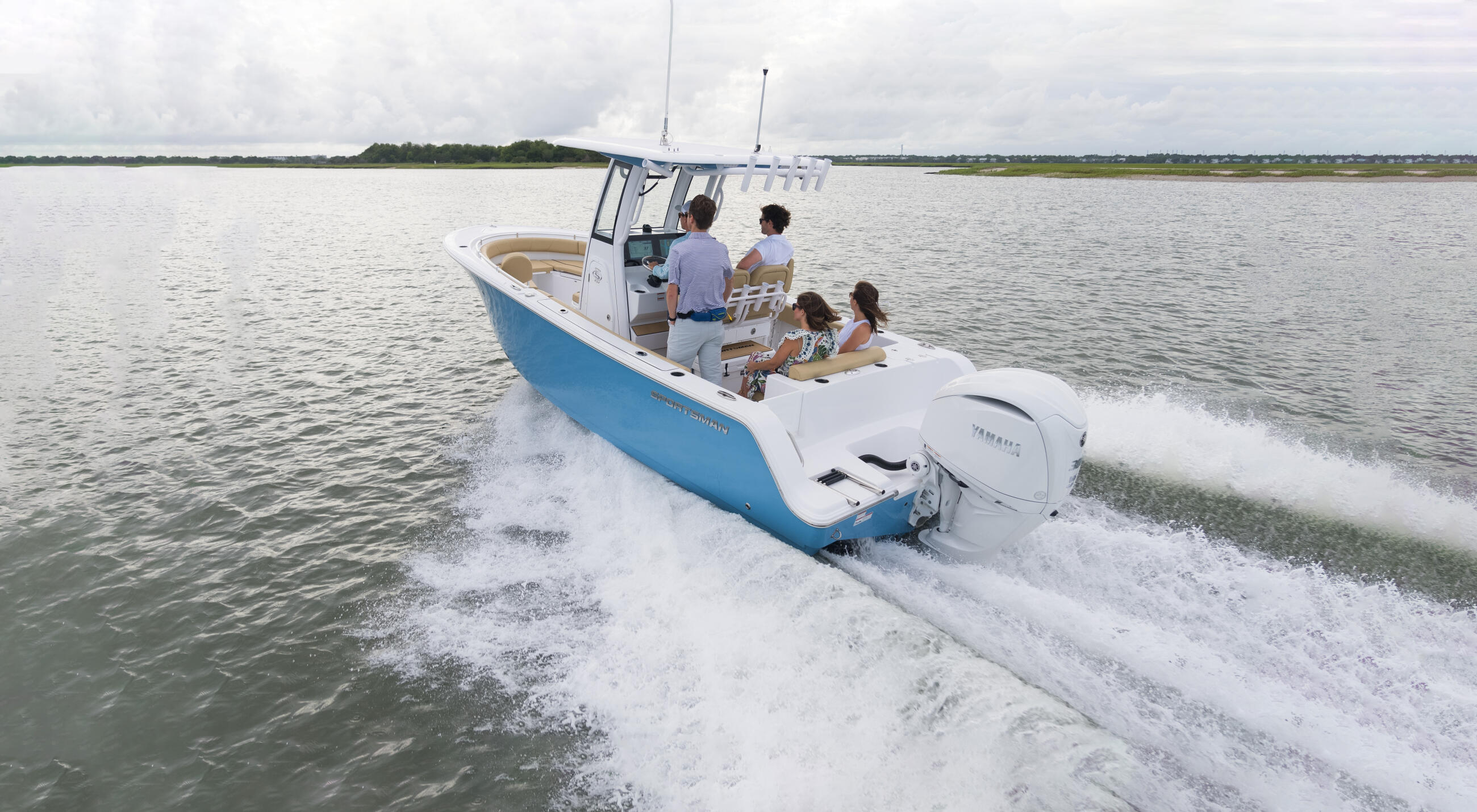 Family of five cruising through shallow coastal waves in a blue and white center console boat
