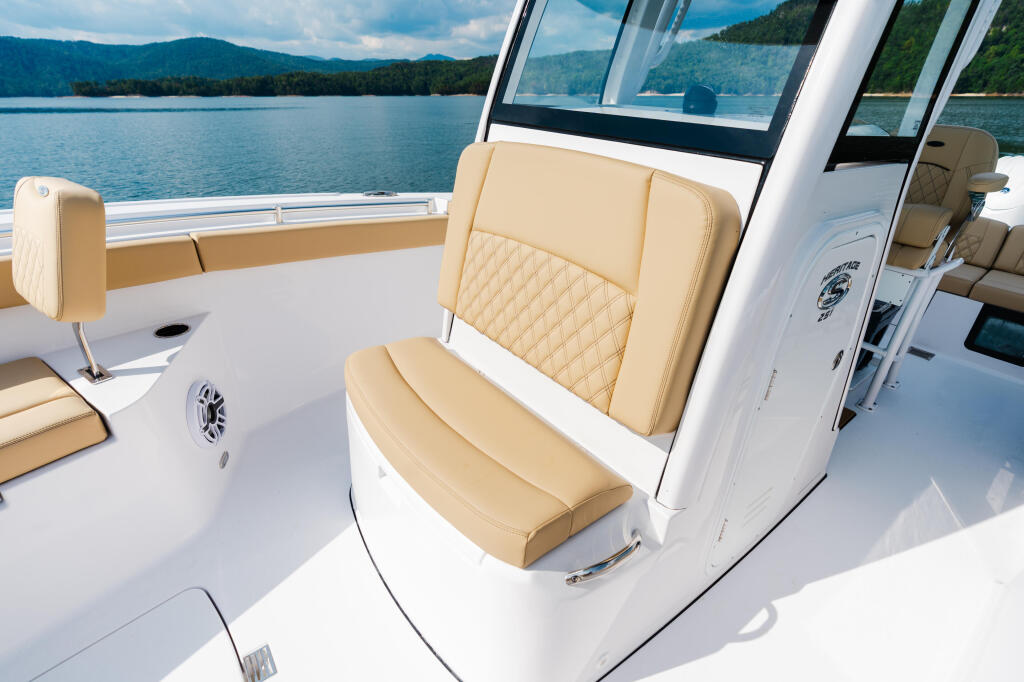 Cream-colored quilted seating and helm area with panoramic windshield overlooking a mountain lake