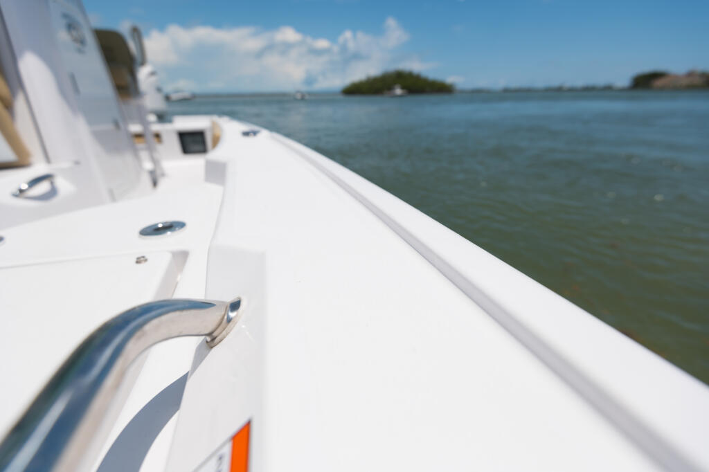 Boat's starboard toe rail and gunwale running along the side with clear water and distant islands visible