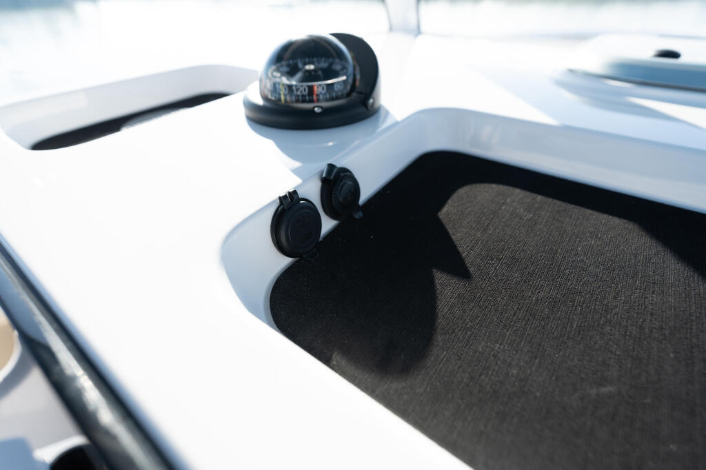 Compass and speakers mounted on white helm console of a boat