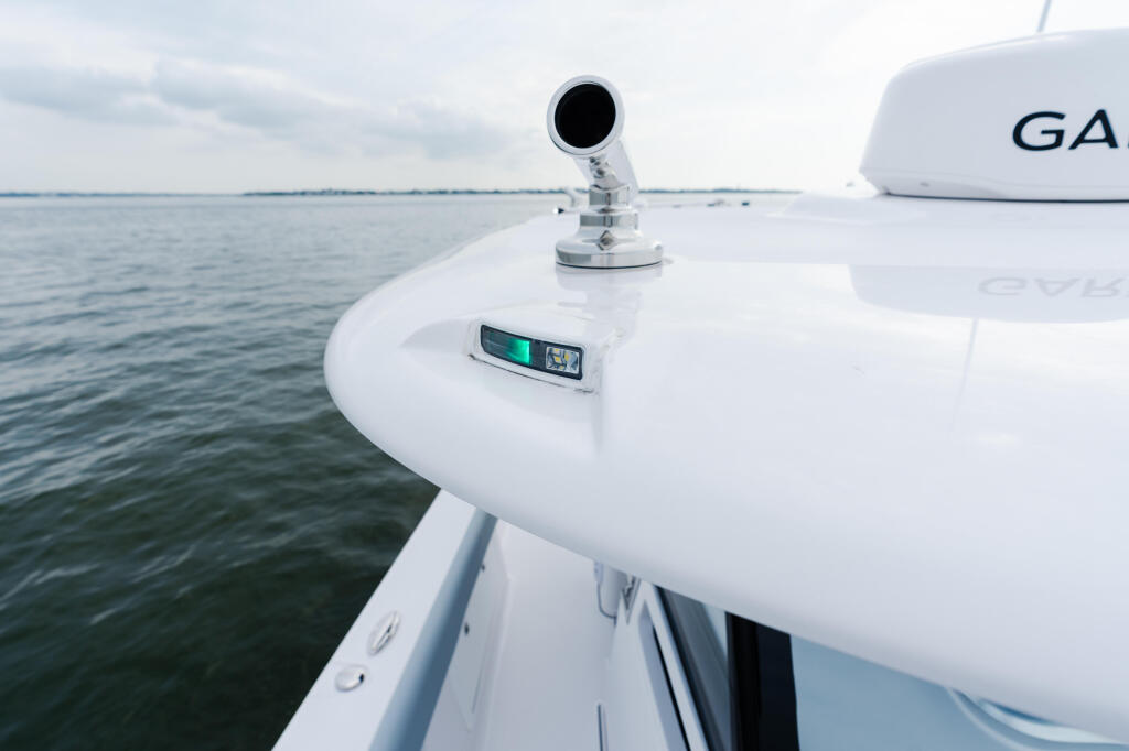 Helm electronics and spotlight mounted on the white hardtop of a boat at sea