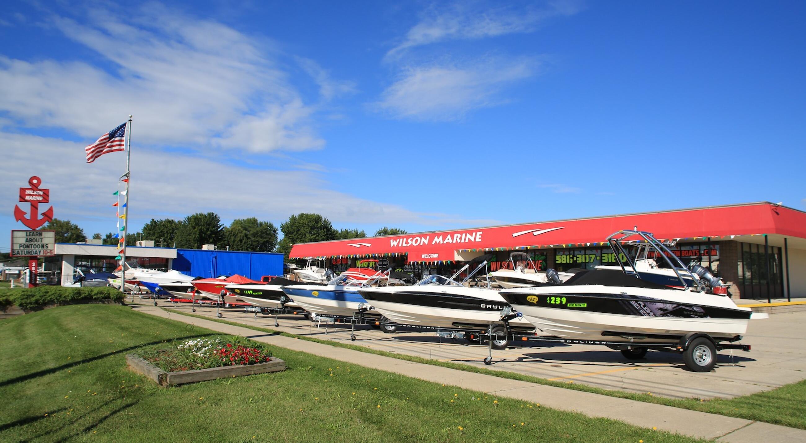 Wilson Marine dealership storefront with multiple boats on trailers in front of red-roofed building